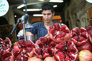 A worker preparing fresh pomegranate juice from these pomegranate fruit. Photo taken at a market in Istanbul, Turkey.